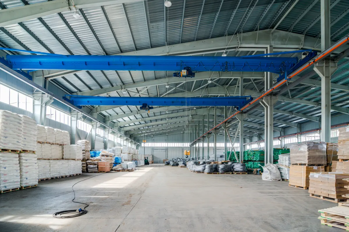Steel industrial shed interior with overhead cranes and stored goods