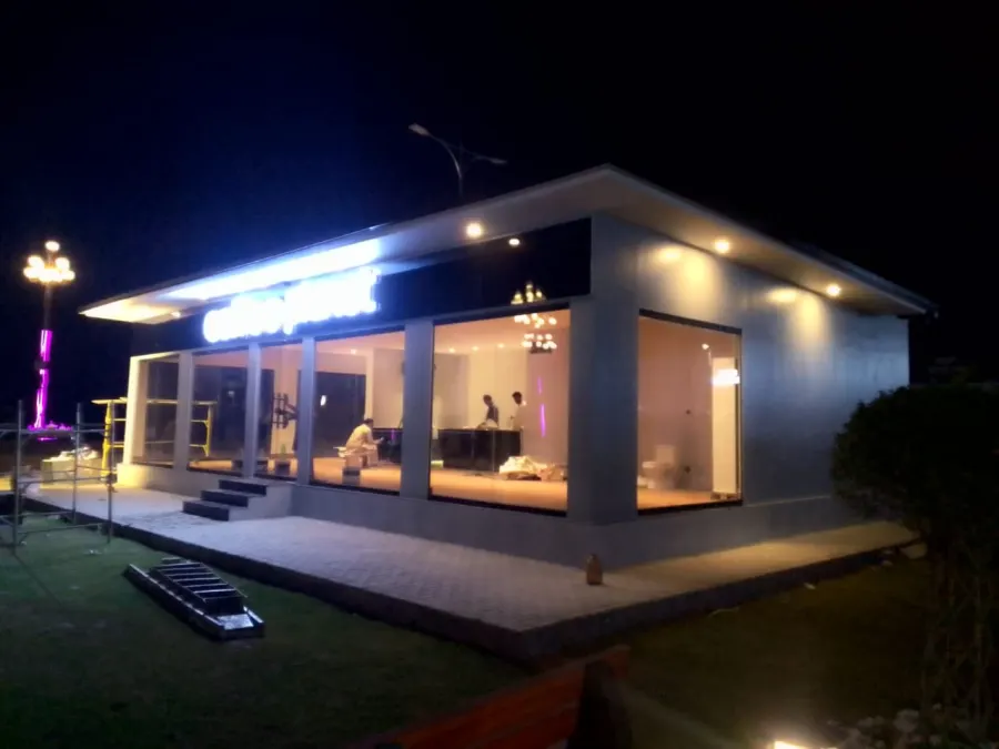 Modern prefabricated café with floor-to-ceiling glass and warm lighting at night